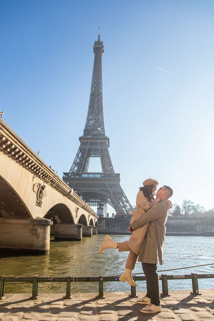 a man holding a woman in front of the eiffel tower