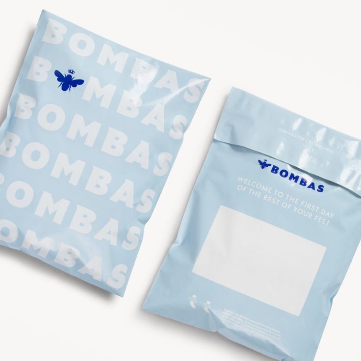 two bags of bombas sitting next to each other on a white surface with blue letters