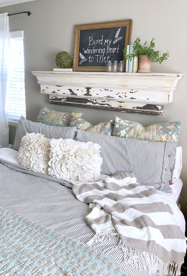 a bed with pillows and blankets on top of it next to a fireplace mantel