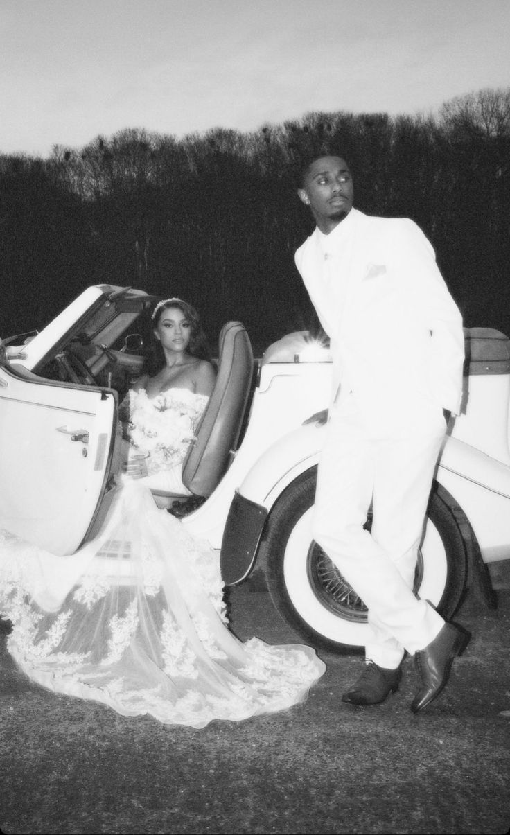 a man and woman standing next to a car