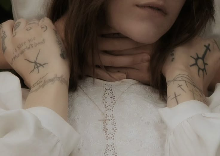 a woman with tattoos on her arms and chest is looking at the camera while laying in bed