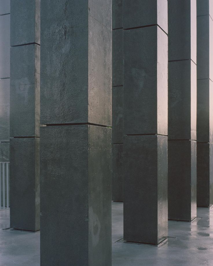 the columns are lined up in an empty room with concrete flooring and cement walls