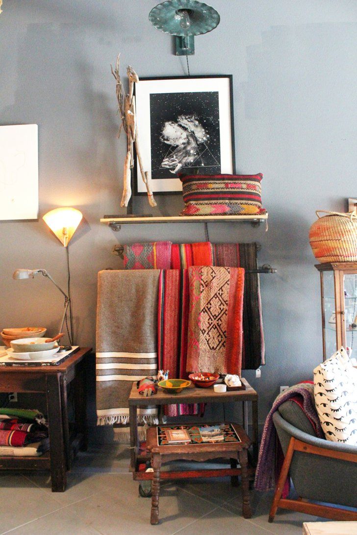 a living room filled with furniture next to a wall covered in blankets and rugs