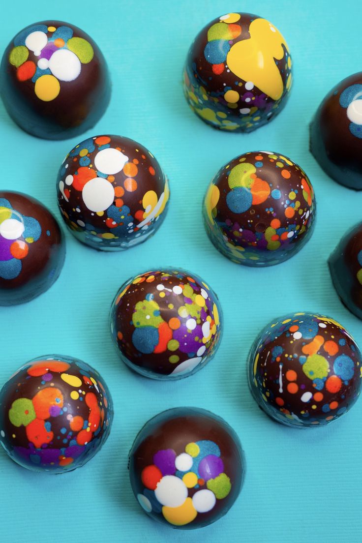 chocolate covered candies with colorful confetti toppings arranged on a blue surface