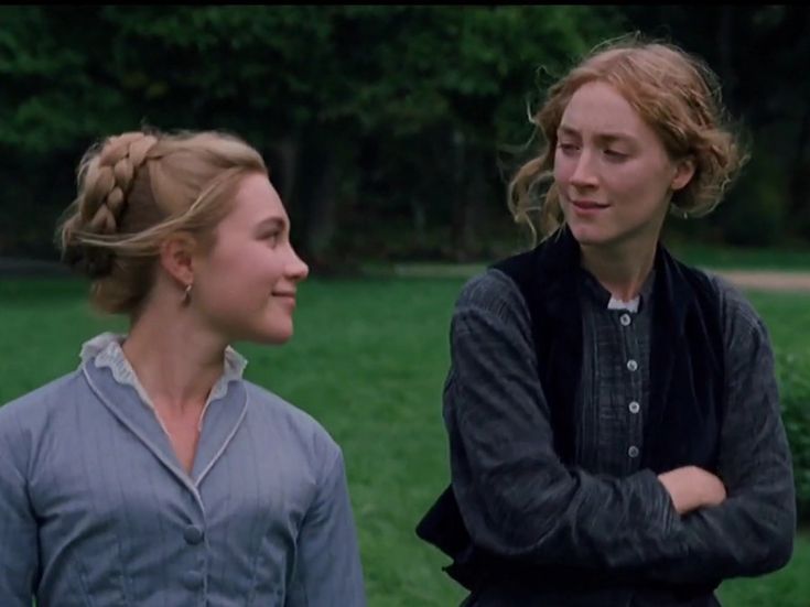 two women standing next to each other in a field