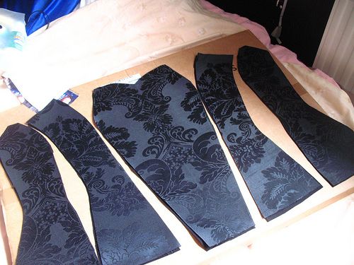 four black ties laid out on a bed