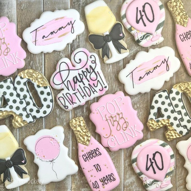 decorated cookies with pink, black and white designs are displayed on a wooden table top