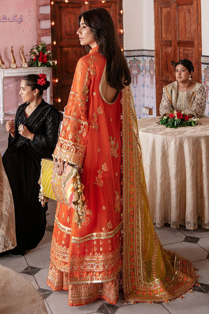 Orange Dress Pakistani in Wedding Gharara Kameez Style is a traditional masterpiece that wins everyone's hearts at the very first glance with its charm and elegance. Embroidery, embellishments, and premium organza fabric make this Gharara Dress an epitome of beauty and grace. Kameez: The beautiful orange kameez in organza fabric looks stunning when paired with gharara. This kameez is emblazoned with classic embroidery work. Beads, sequins, motifs, and threads give a traditional touch to this per Net Gharara Designs, Orange Dress Pakistani, Wedding Gharara, Nazia Hassan, Kameez Style, Mohsin Naveed Ranjha, Gharara Designs, Dress Pakistani, Dupatta Style