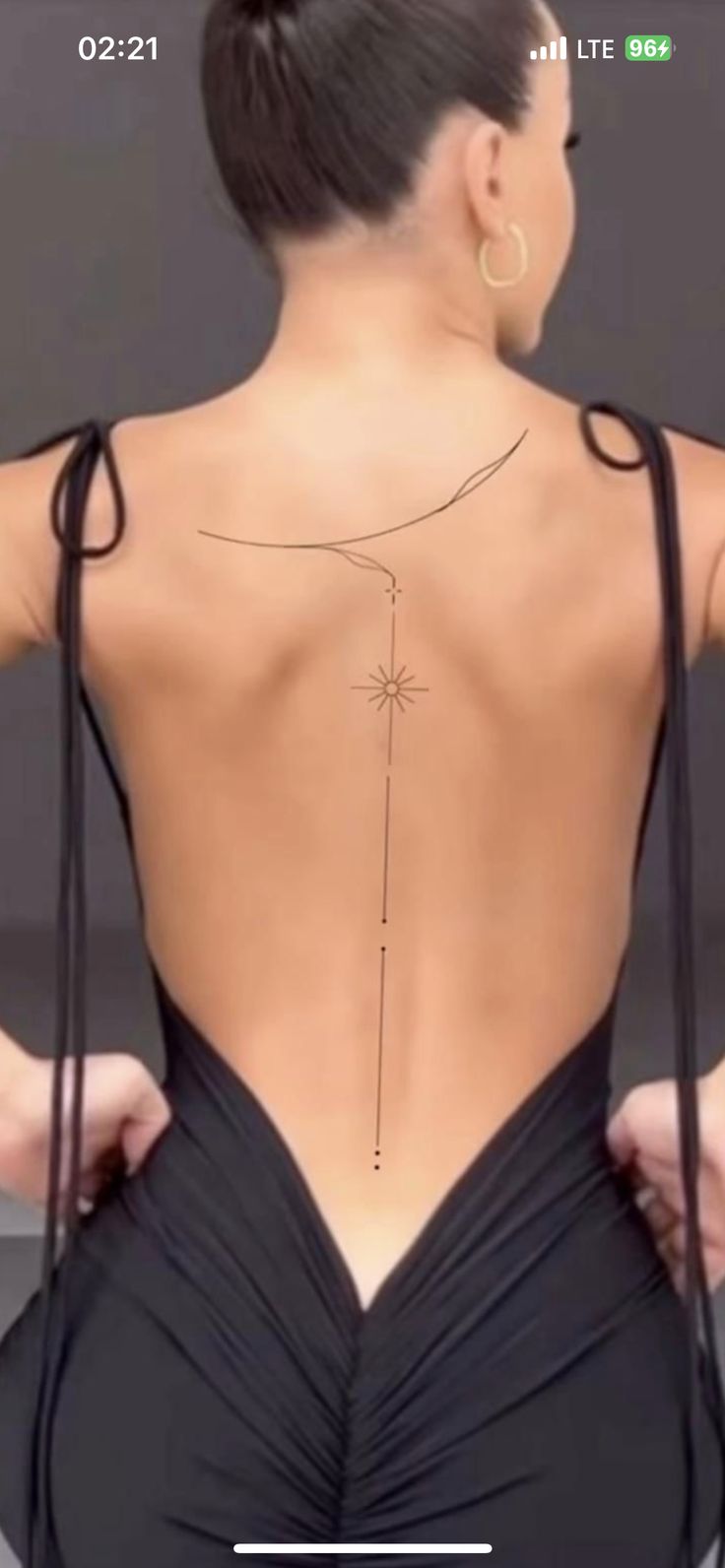 the back of a woman's body with an arrow tattoo on her left shoulder