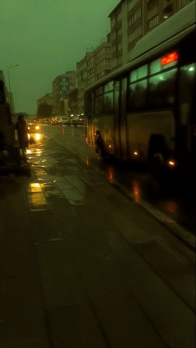 the city bus is driving down the street at night time, with its lights on