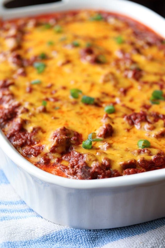 a casserole dish with meat and cheese in it on a blue and white towel