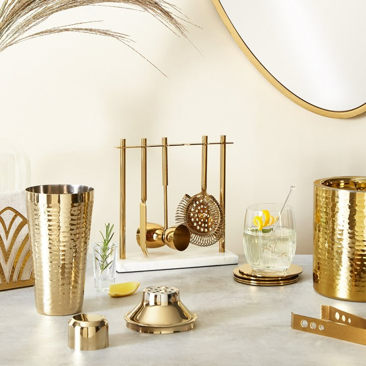 a table topped with gold vases and other decorative items on top of a white counter