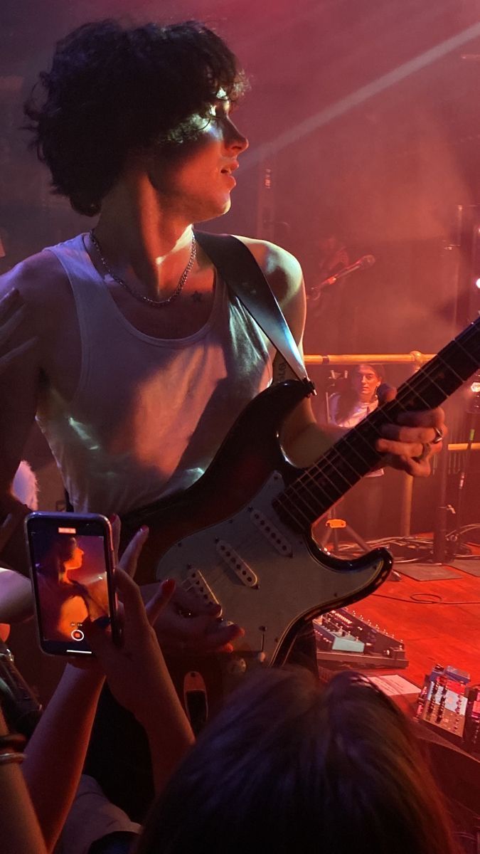 a woman with an electric guitar in front of a group of people at a concert