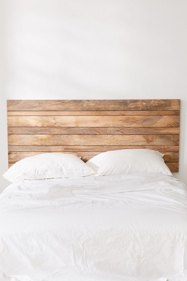 a bed with white linens and wooden headboard