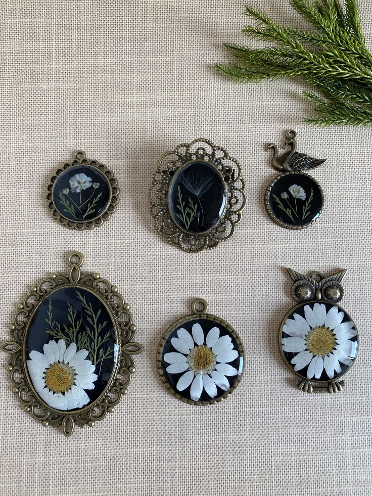 six pendants with white flowers on them sitting next to a pine branch and green sprig