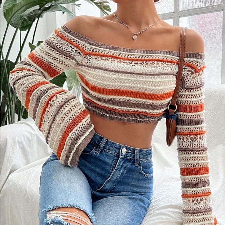 a woman sitting on a couch wearing ripped jeans and a striped off the shoulder top