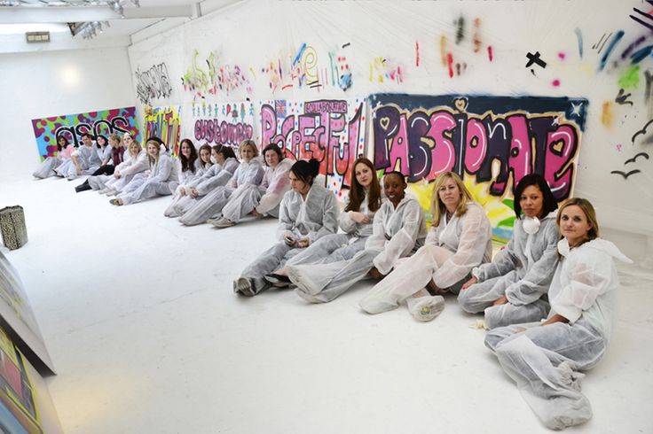 a group of women sitting on the floor in front of graffiti covered walls