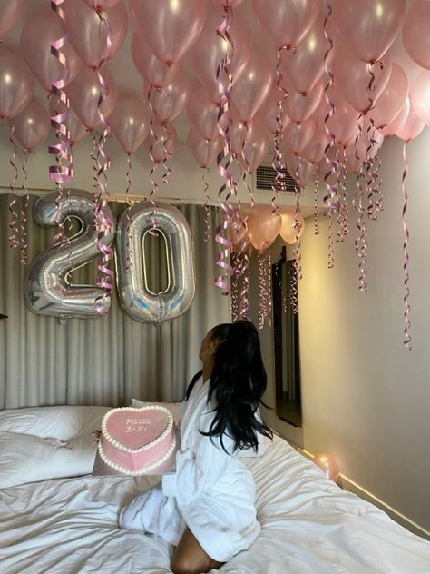 a woman sitting on top of a bed under balloons