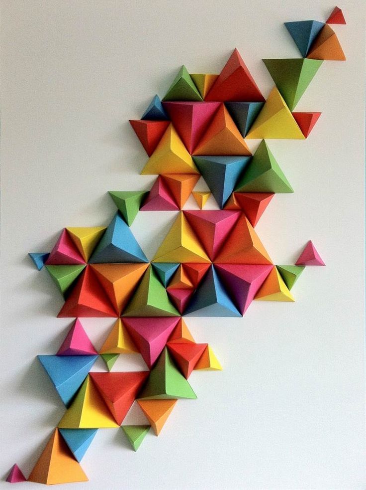 colorful origami pieces are arranged on the wall