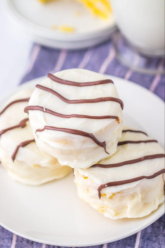 three cookies with white frosting and chocolate drizzled on them sitting on a plate