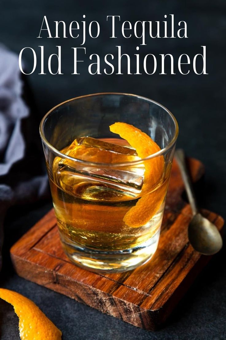 an old fashioned drink is served in a glass with orange peels on the side