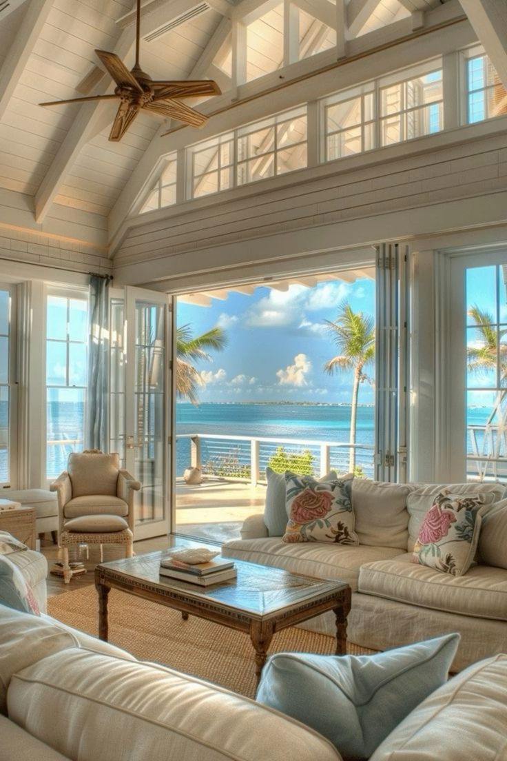 a living room filled with lots of furniture next to an ocean front window covered in palm trees