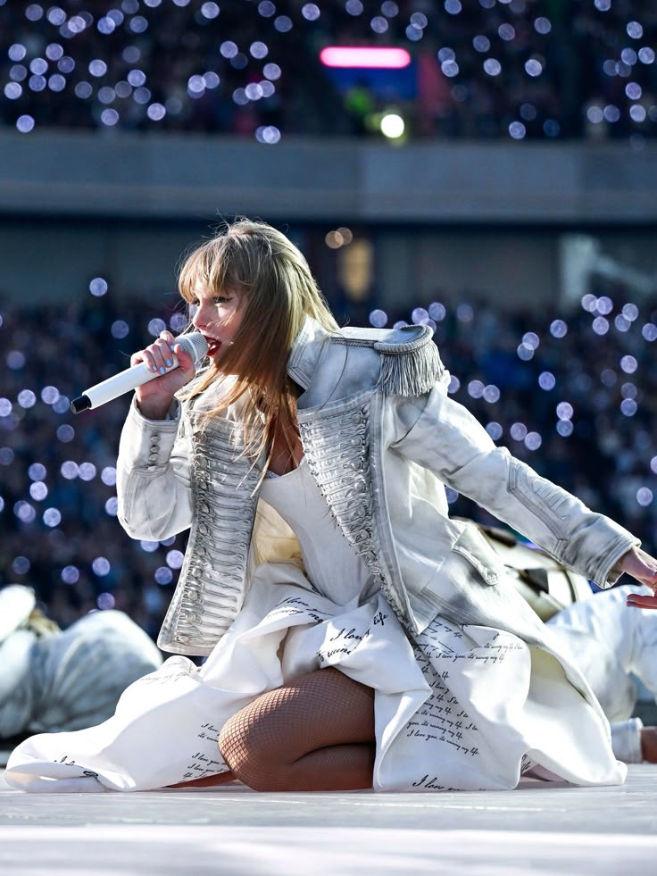 a woman is sitting on the ground with a microphone in her hand and she is singing