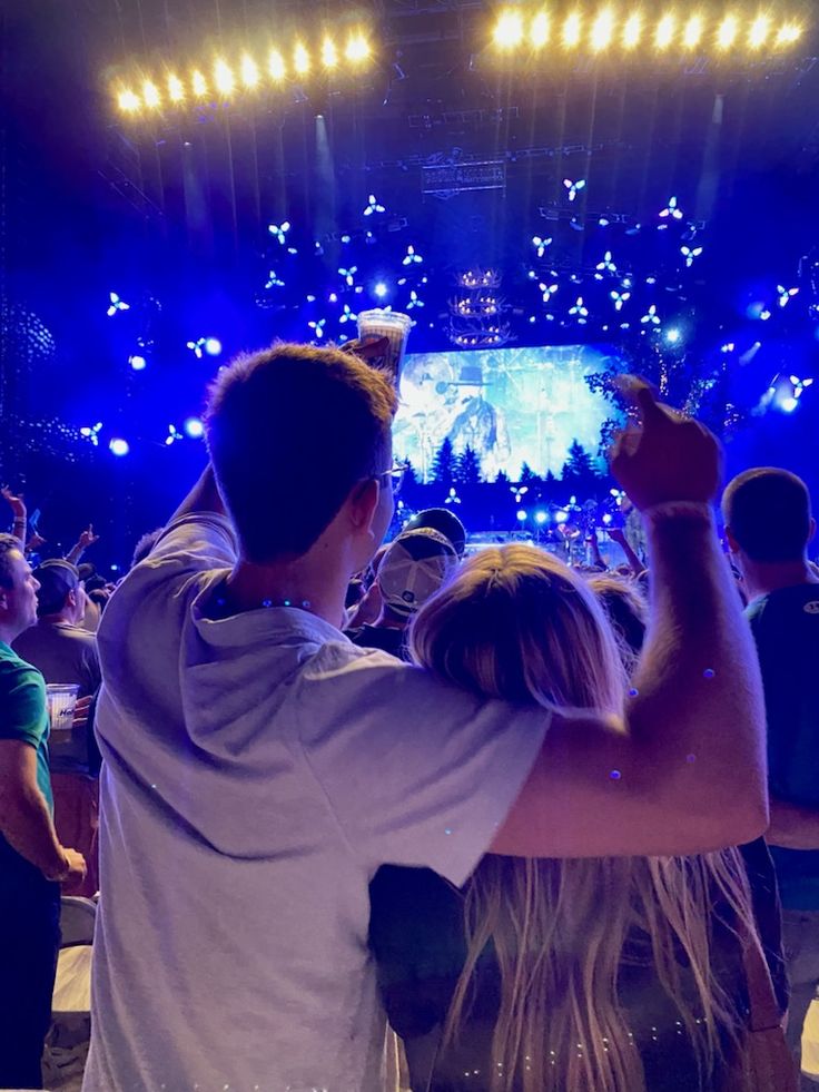 two people standing in front of a crowd at a concert