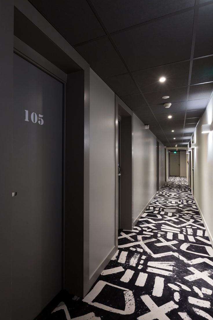 a long hallway with black and white carpeting on the floor next to two doors