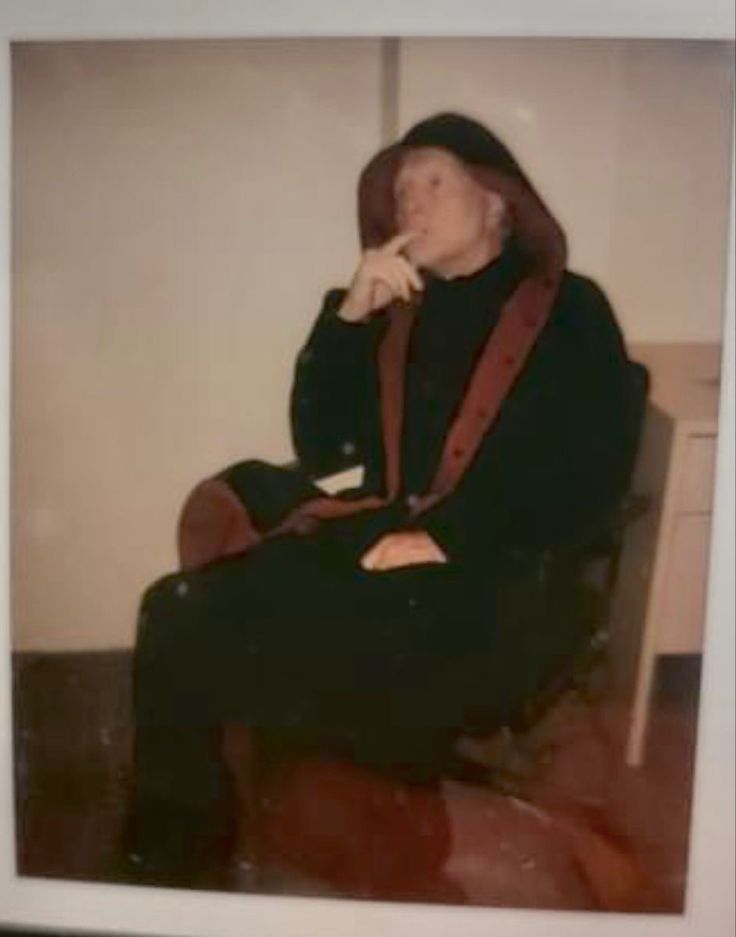 an old black and white photo of a woman sitting in a chair with her hand on her chin