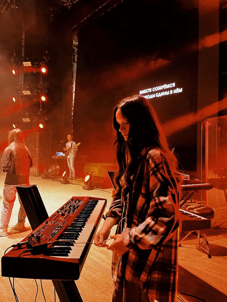 a woman standing next to a keyboard on top of a hard wood floor in front of a crowd