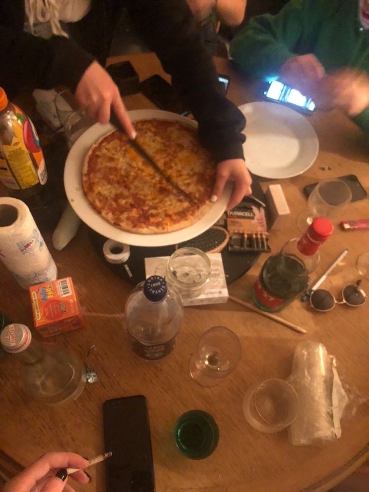 people sitting at a table with pizza and drinks