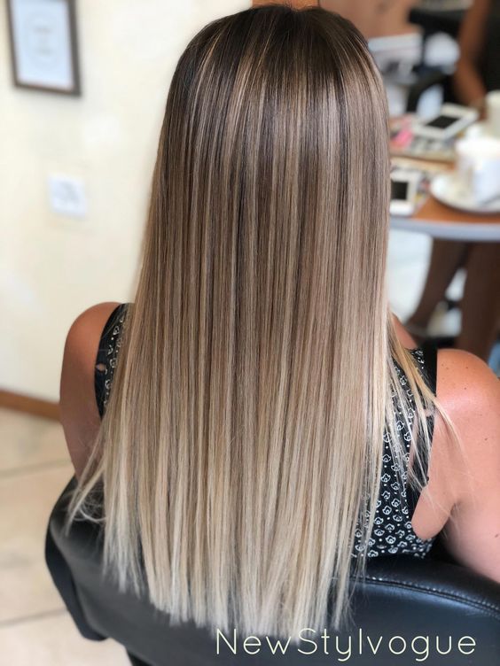 the back of a woman's head with long blonde hair sitting in a chair