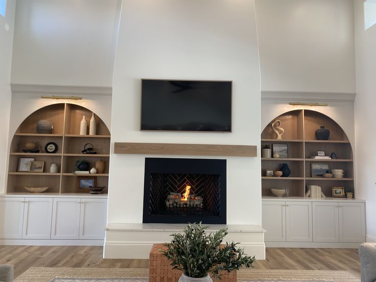 a living room filled with furniture and a flat screen tv mounted on the wall above a fire place