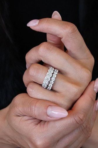 a woman's hands holding an engagement ring with two rows of diamonds on it