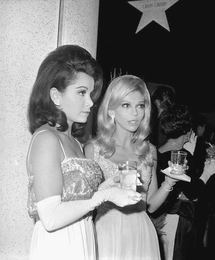 two women standing next to each other holding wine glasses