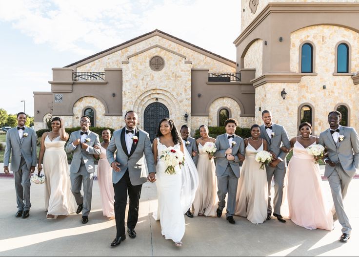 a bride and groom with their bridal party in front of a large stone church