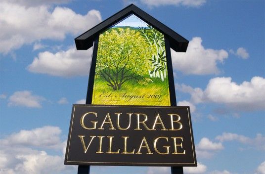 a sign for gaurab village in front of a blue sky with clouds