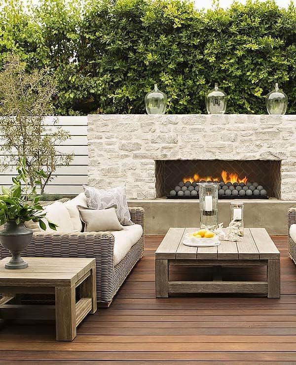 an outdoor living area with couches, tables and fire place in the middle of it