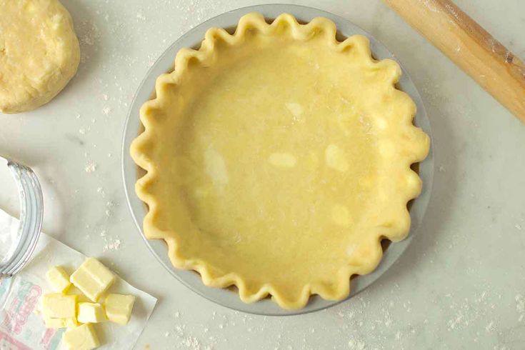 an uncooked pie crust sits on a table next to other baking supplies