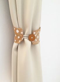 a white curtain with brown polka dots and a wooden button on the side, hanging from a metal rod