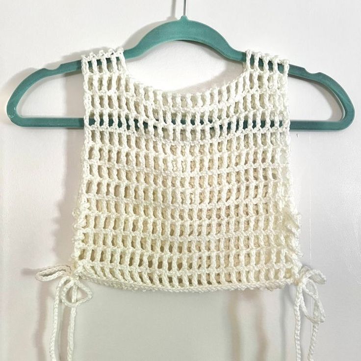 a white crochet top hanging on a green hanger