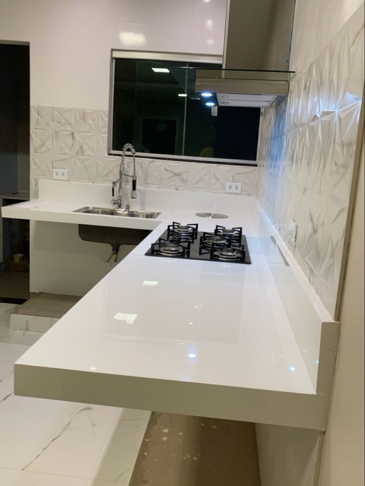 a white kitchen counter top sitting under a window next to a stove top oven and sink