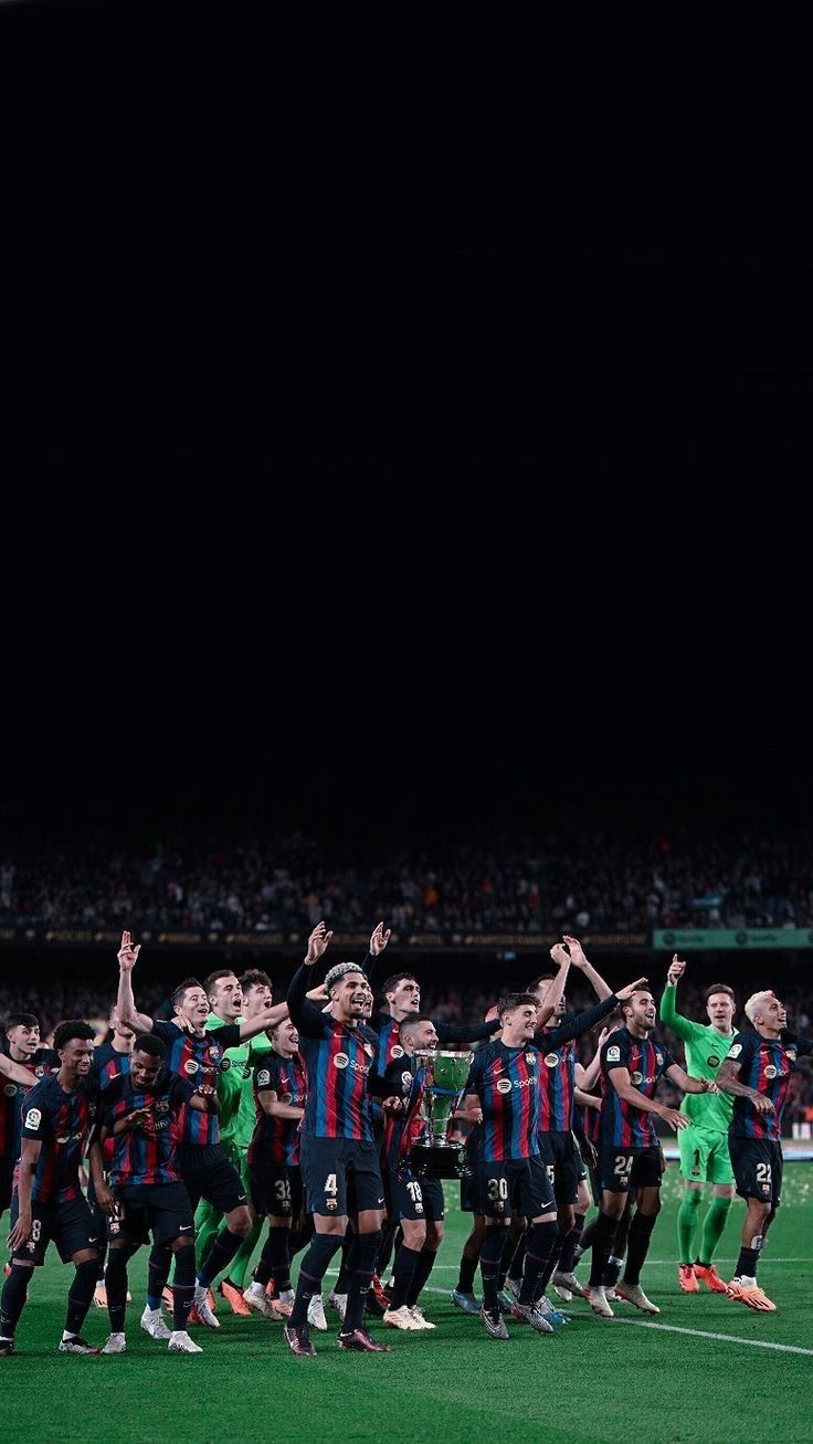 a group of men standing on top of a soccer field holding hands in the air