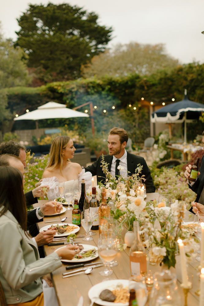 a group of people sitting around a table with food and drinks in front of them