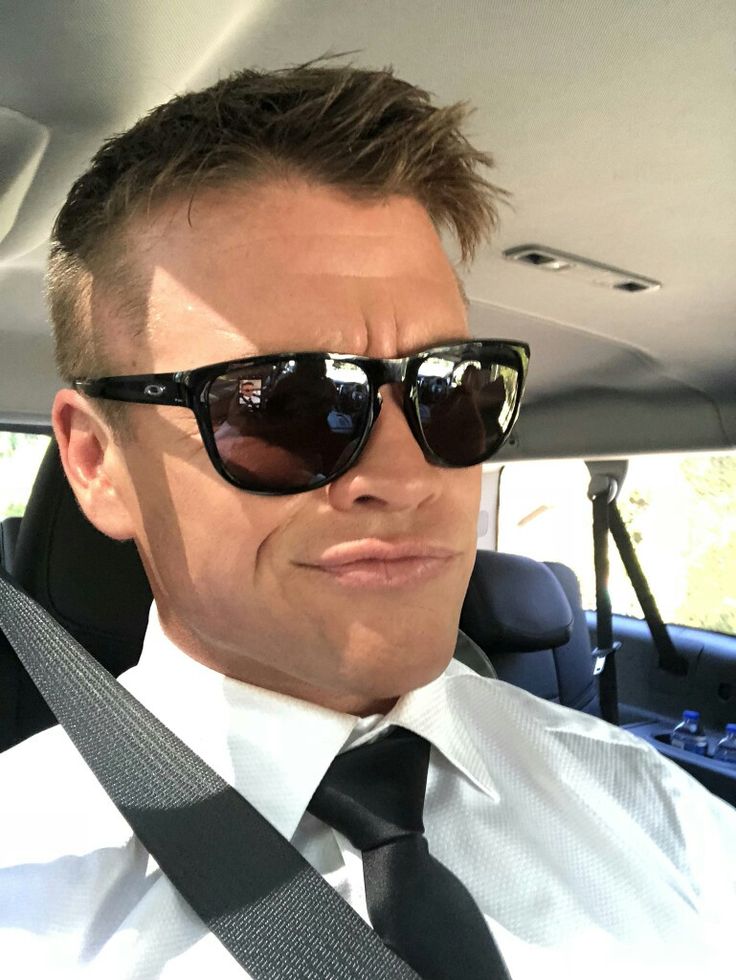 a man wearing sunglasses and a tie sitting in a car