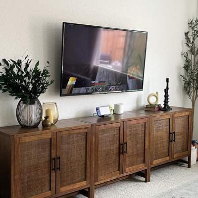 a flat screen tv mounted to the side of a wooden cabinet in a living room