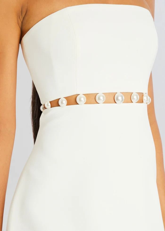 a woman is wearing a white dress with pearls on the waist and an embellished belt