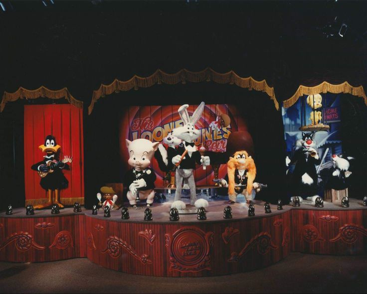 several stuffed animals are on stage in front of a red curtain