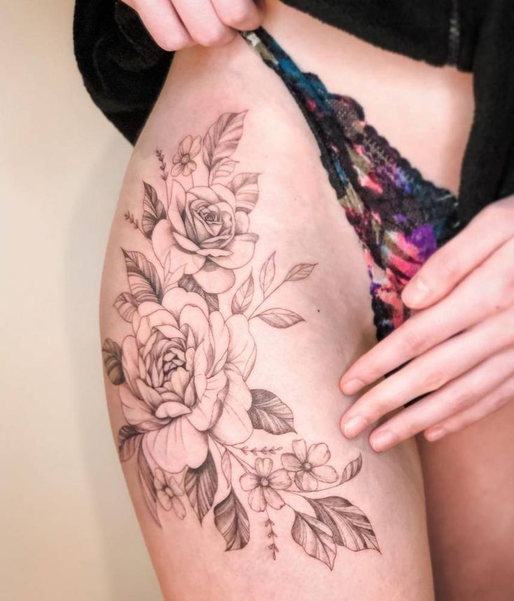 a woman is showing off her thigh with flowers on it